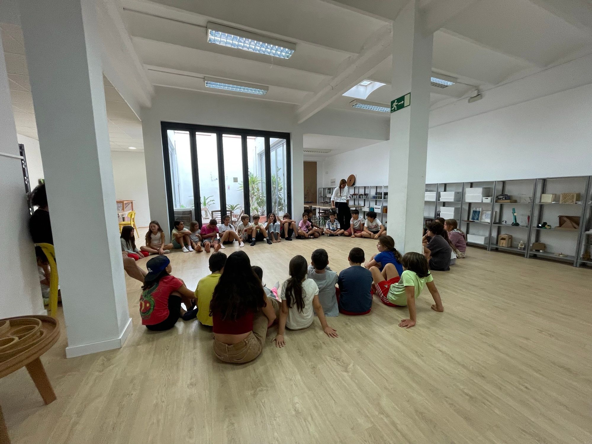 Assembly: the children sitting in a circle on the floor of a bright room