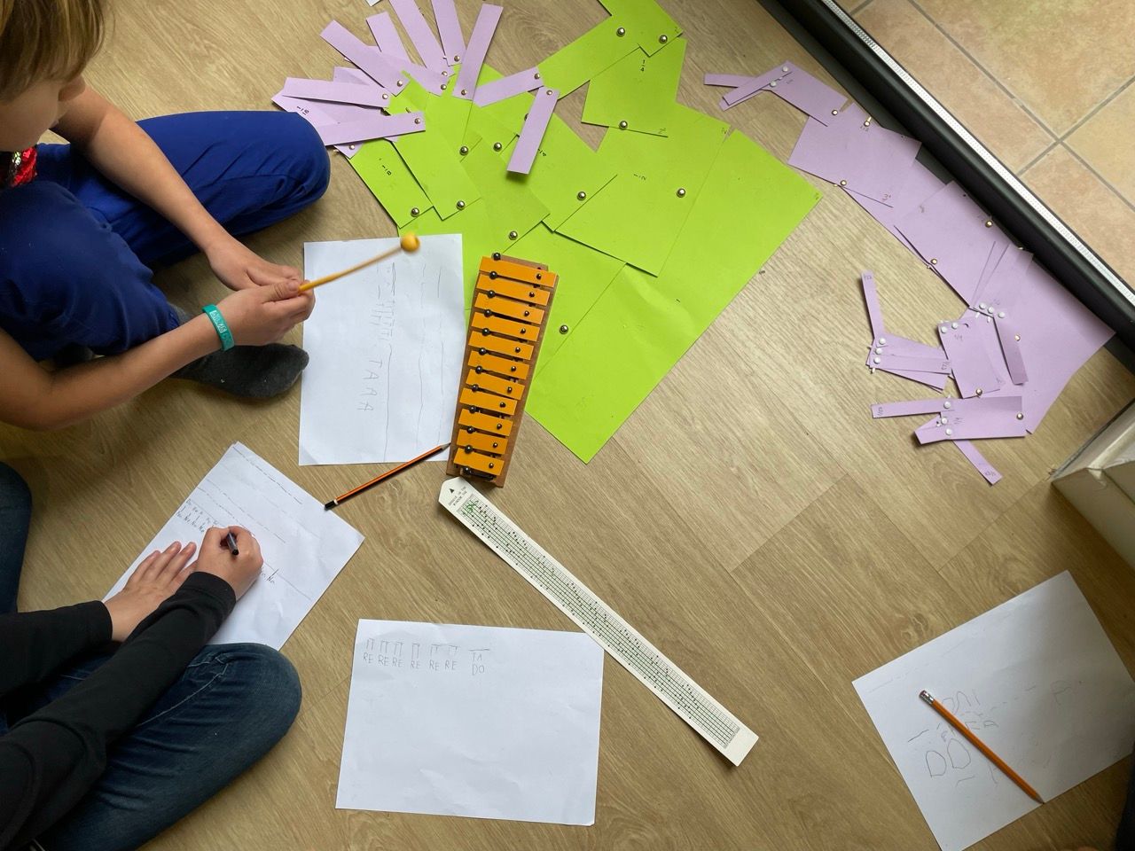 A xylophone on the floor, hand-written scores and coloured card