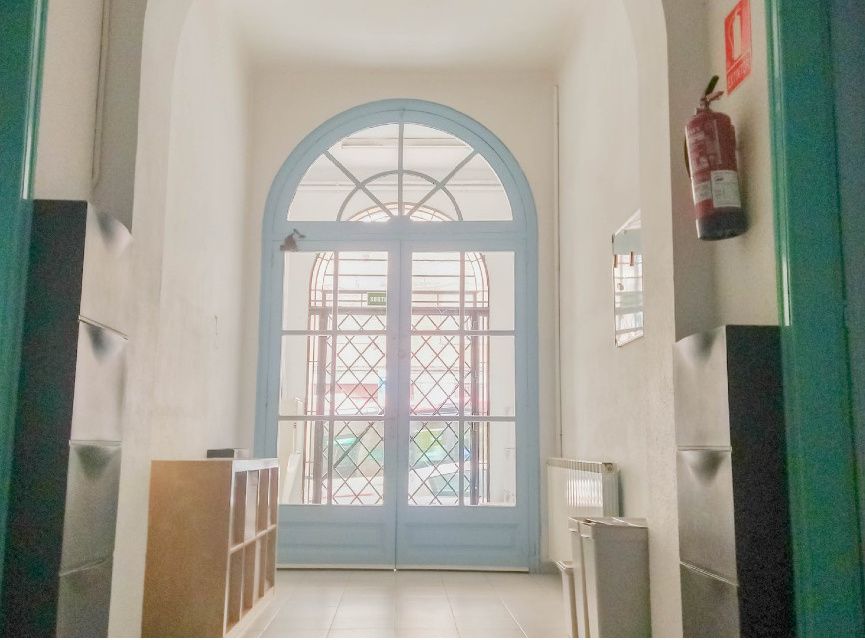 Puerta de arco del vestíbulo de la escuela, con la reja y la luz del patio