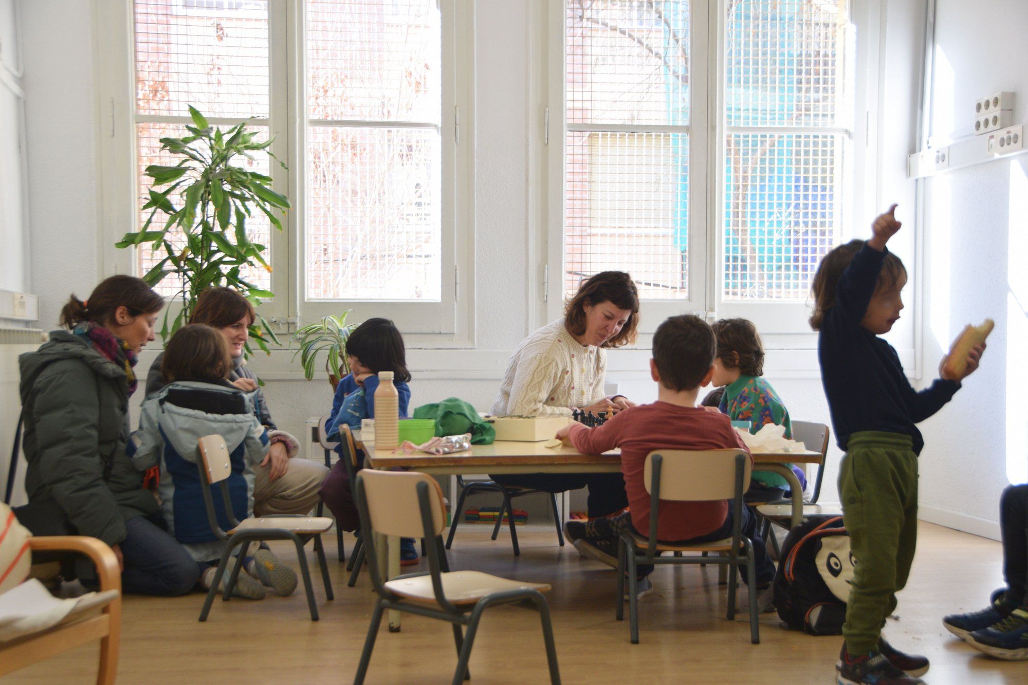 Early drop-off care: children and adults playing round a table