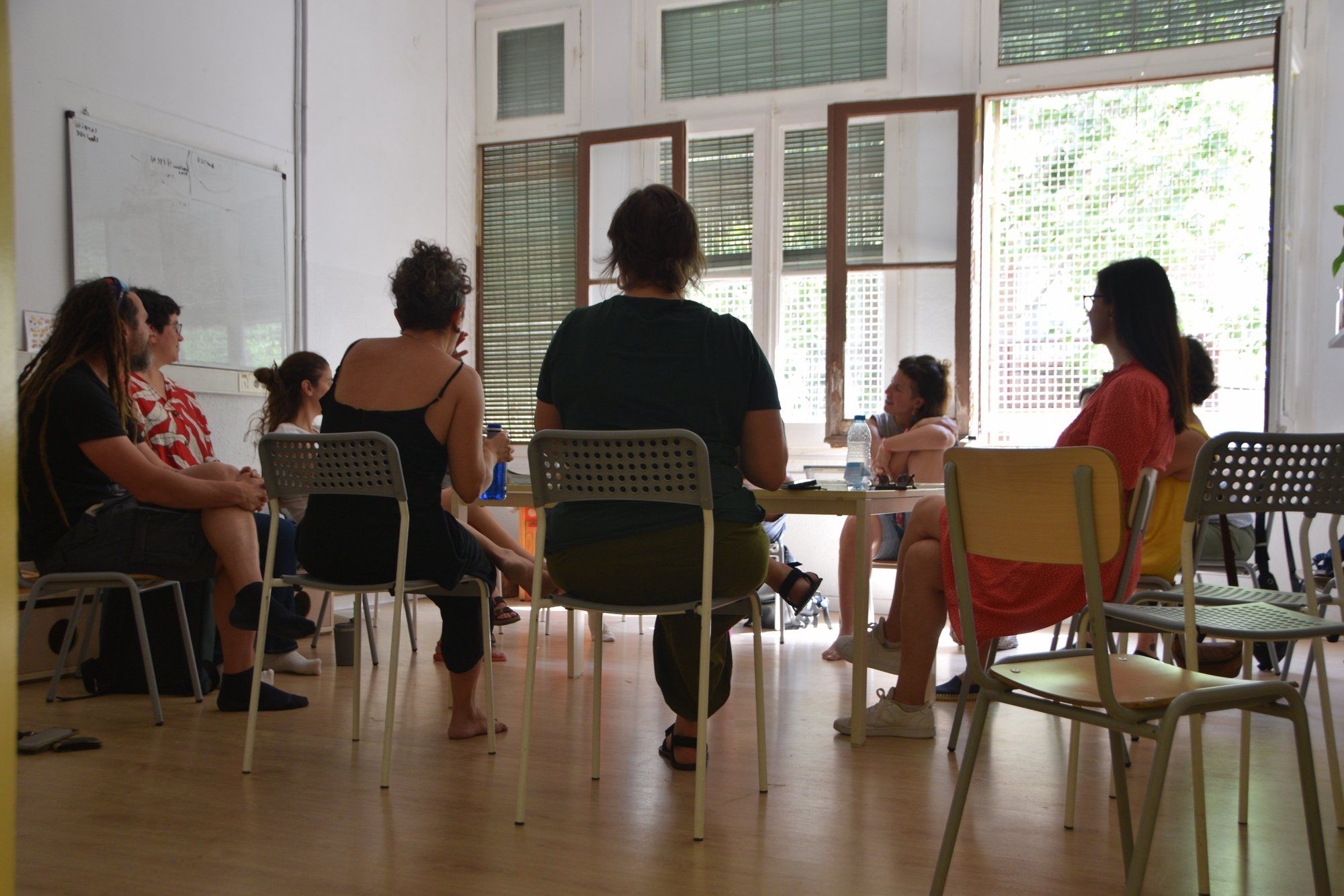 A families’ meeting, everyone sitting in a circle in a bright room