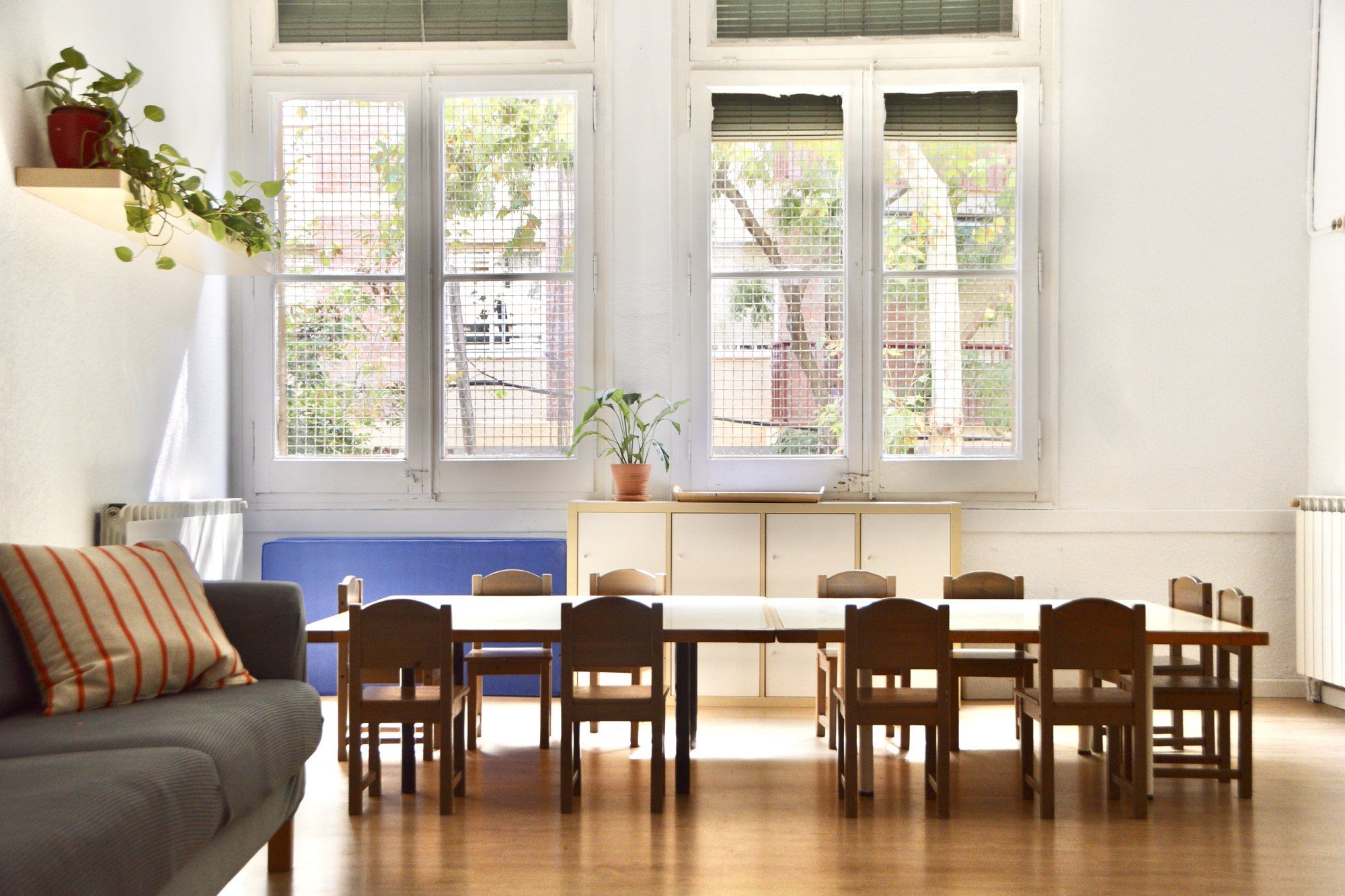 Early years workshop room, with a long table, small wooden chairs and a sofa