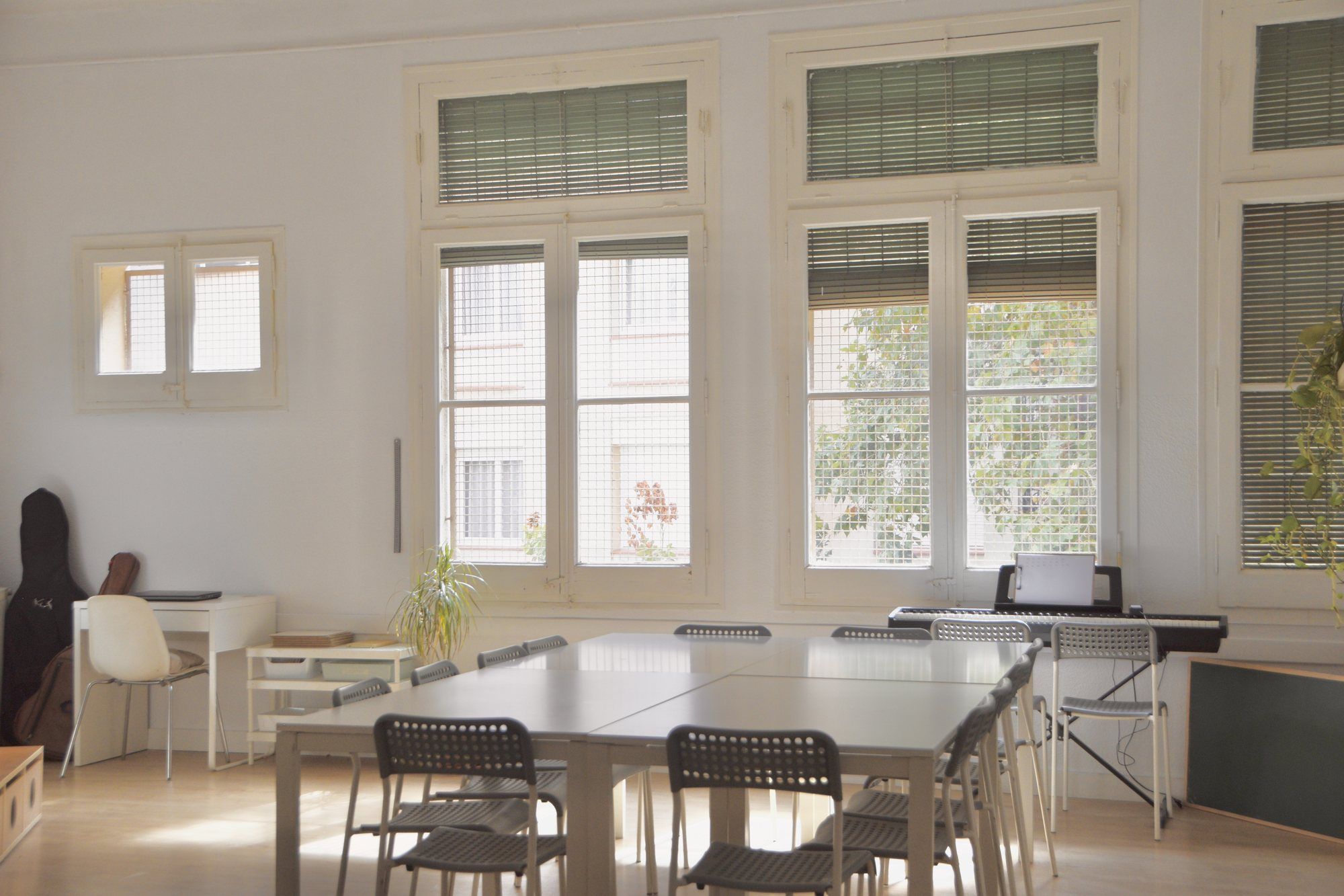 Upper primary room, with grey tables, a keyboard and a guitar